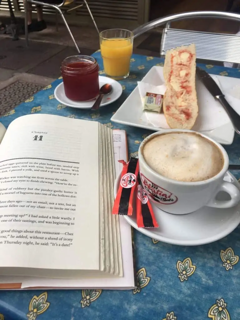 an open book, coffee, jam and bread on a table an open book, coffee, jam and bread on a table